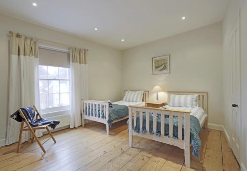 a bedroom with two beds and a chair and a window at 33 Victoria Street in Southwold