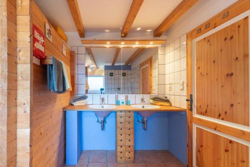 ノイキルヒェンにあるKleinwindsteinの木製の壁の客室には洗面台2台付きのバスルームが備わります。