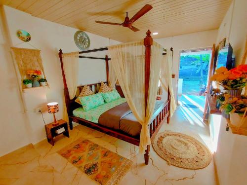 a bedroom with a canopy bed with a ceiling fan at EcoZen Holiday Rooms in Agonda