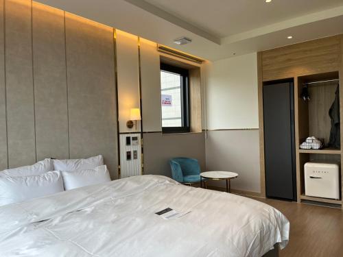 a bedroom with a large white bed and a chair at H avenue Kijang Ilgwang in Busan