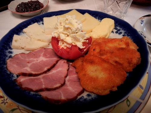 a plate of food with meat and cheese on a table at Pensiunea Casa-Stefanel in Sadova