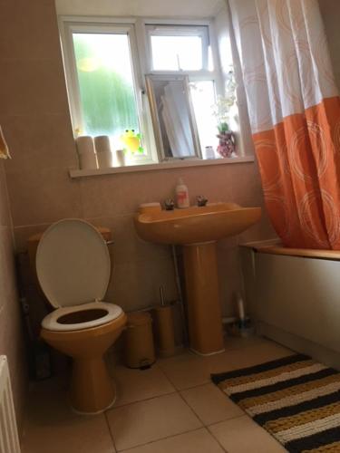 uma casa de banho com um WC, um lavatório e uma janela em Comfy rooms. Shared East London Homestay. em Londres