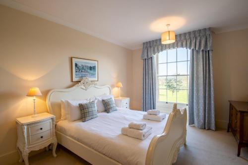 um quarto com uma grande cama branca com toalhas em Garden Wing, Redisham Hall em Beccles