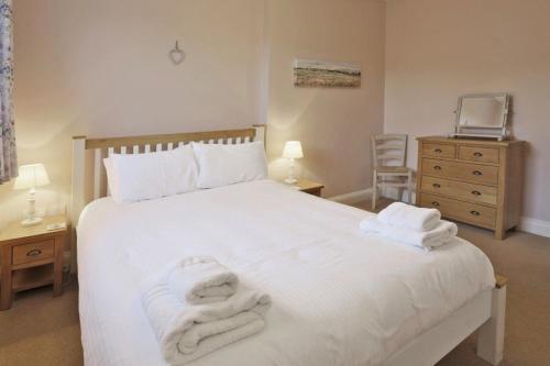 a bedroom with a white bed with towels on it at Happy Days in Southwold