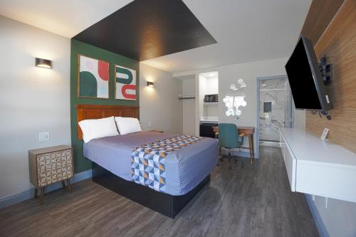 um pequeno quarto de hotel com uma cama e uma secretária em Sunrise Inn by OYO Titusville FL em Titusville