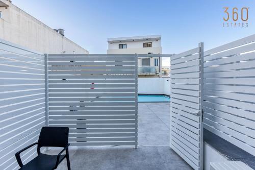 a chair sitting on a patio with a fence at The Swieqi Poolside Suites in Is-Swieqi