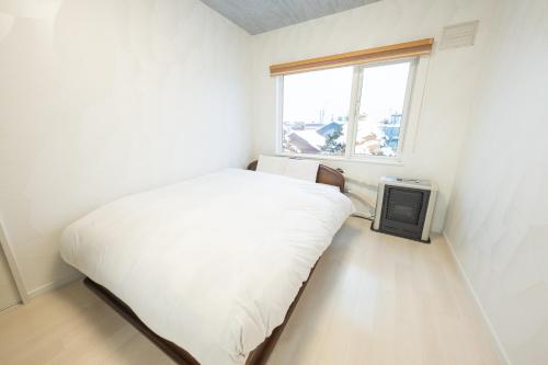 a small bedroom with a bed and a window at furano ski rabi in Furano