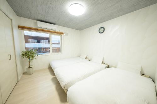dwa łóżka w pokoju z zegarem na ścianie w obiekcie furano ski rabi w mieście Furano