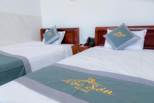 two beds in a hotel room with a sign on them at Lộc Sơn Hotel in Buon Ma Thuot