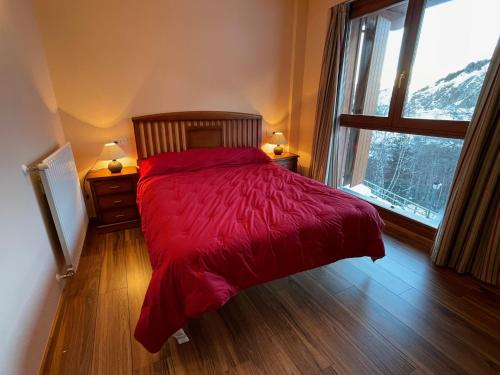 a bedroom with a bed with a red comforter and a window at Soldeu Paradis Pleta 2 in Soldeu