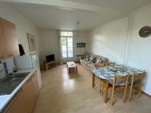 a kitchen and living room with a table and a couch at Les Platanes - Gaugain in Lamalou-les-Bains