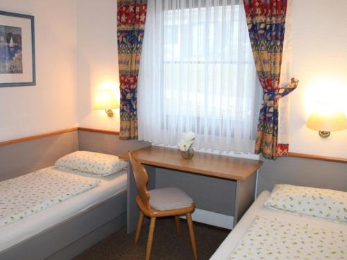 Cette chambre comprend deux lits, un bureau et une chaise. dans l'établissement Ferienhaus Nr 21, Kategorie Komfort, Feriendorf Hochbergle, Allgäu, à Bichel