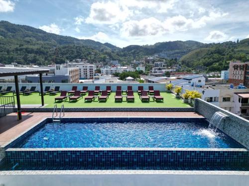 a swimming pool on the roof of a building with chairs at Paripas Patong Resort in Patong Beach