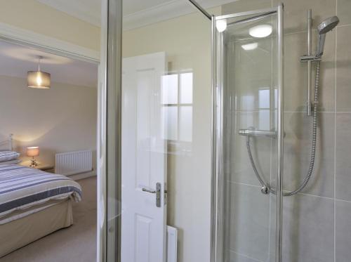 uma casa de banho com um chuveiro e uma porta de vidro em Jubilee View em Southwold
