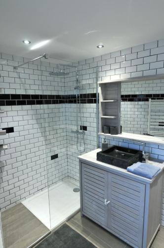 La salle de bains est pourvue d'une douche, d'un lavabo et de carrelage blanc. dans l'établissement La terrasse, à Étretat