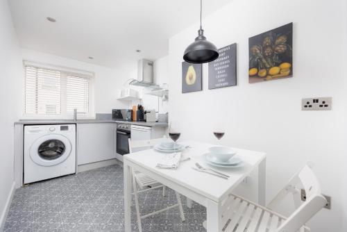 cocina blanca con mesa y lavadora en Perfect Getaway - Central Plymouth Apartment - Sleeps 4 - By Habita Property en Plymouth