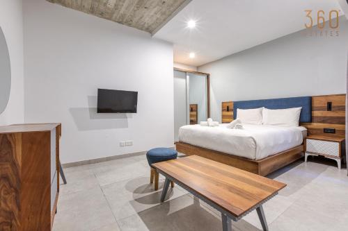 a bedroom with a bed and a table and a tv at The Swieqi Poolside Suites in Is-Swieqi