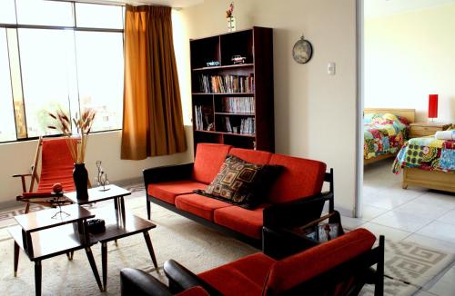 a living room with a red couch and a book shelf at Taytaypa Rooms & Apartments Lima Airport in Lima