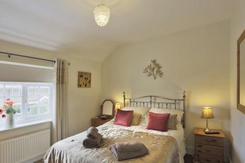 Un dormitorio con una cama con almohadas rojas y una ventana en Little Blue Cottage, en Southwold