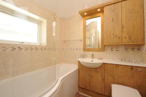 y baño con bañera, lavabo y bañera tubermottermott. en Little Blue Cottage, en Southwold
