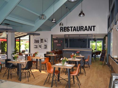 een restaurant met tafels en stoelen en een restaurantbord bij ibis Abbeville in Abbeville