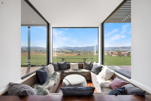 a living room with a large couch and large windows at Merrivale Hill, Merrijig - Sleeps 10 in Merrijig