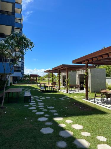 a park with picnic tables and benches in front of a building at Blue Beach Beira Mar in Cabedelo