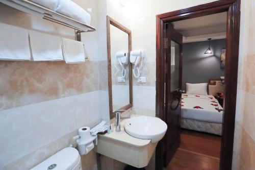a bathroom with a sink and a mirror and a bed at Hortensia Flower in Hanoi