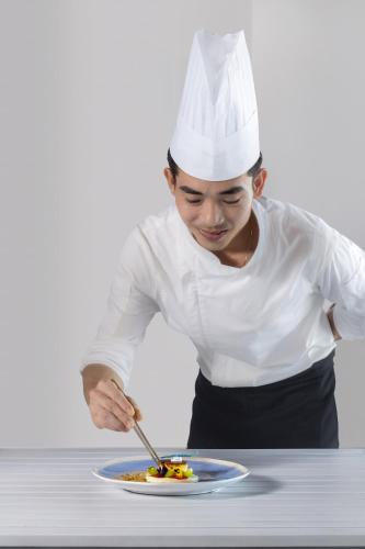 a woman in a chefs hat preparing a plate of food at Melia Danang Beach Resort in Da Nang