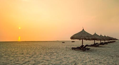 a row of umbrellas on a beach at sunset at Melia Danang Beach Resort in Da Nang