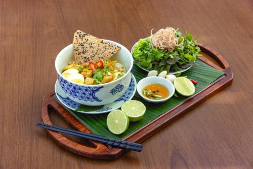 a tray with a bowl of food and a plate of food at Melia Danang Beach Resort in Da Nang