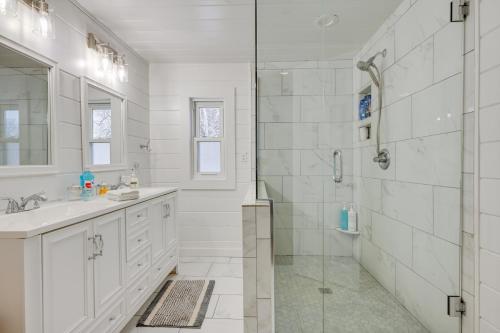 a white bathroom with a shower and a sink at Lakefront Fenton Retreat with Decks and Fire Pit! in Fenton