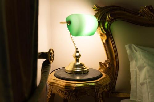 a green lamp sitting on a table next to a bed at San Giorgio Rooms in Genova