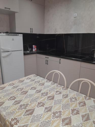 a kitchen with a table and chairs and a refrigerator at Алпамыс in Prigorodnyy