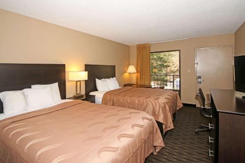 a hotel room with two beds and a flat screen tv at Quality Inn Clinton - Laurens I-26 in Clinton
