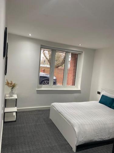 a white bedroom with a bed and a window at Entire Apartment perfectly located for Heathrow Airport in Uxbridge
