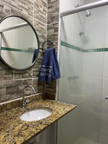 a bathroom with a sink and a shower with a mirror at Praia de Itaparica com Vista para o Mar in Vila Velha