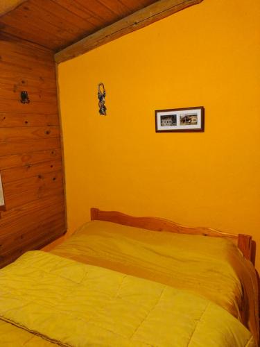 1 dormitorio con 1 cama en una habitación amarilla en Cabaña villa del lago en Lago Puelo