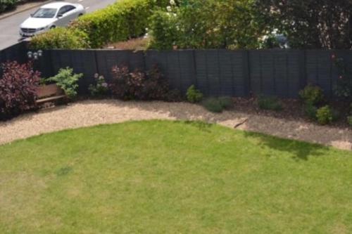 a backyard with a fence and a yard with a lawn at Entire Apartment perfectly located for Heathrow Airport in Uxbridge