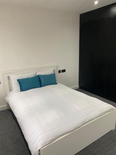 a large white bed with two blue pillows on it at Entire Apartment perfectly located for Heathrow Airport in Uxbridge