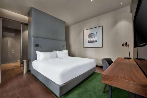 a bedroom with a large white bed and a desk at Hilton Porto Gaia in Vila Nova de Gaia