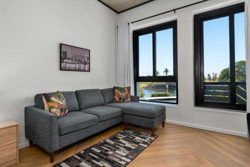 sala de estar con sofá gris y ventanas en Bridgewater One Apartments, en Ciudad del Cabo