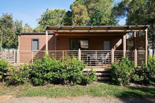 a wooden cabin with a porch and a fence at Camping Campo dei Fiori in Vada