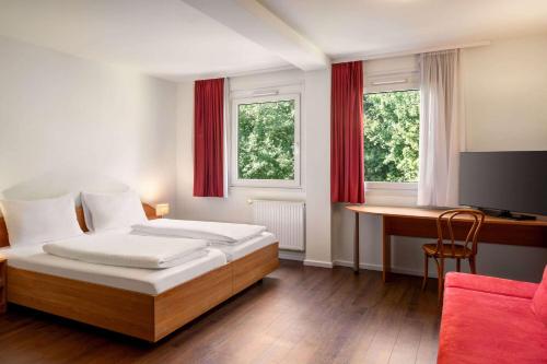 Schlafzimmer mit einem Bett und einem Schreibtisch mit einem Computer in der Unterkunft Amedia Express Sattledt, Trademark Collection by Wyndham in Sattledt