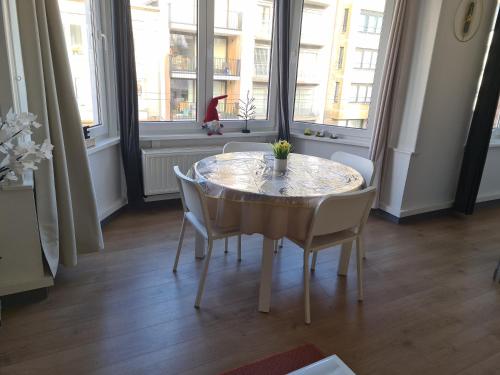 a dining room with a glass table and chairs at Appartement avec parking 50 m de la mer in De Panne