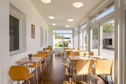 a restaurant with tables and chairs and windows at Amedia Express Sattledt, Trademark Collection by Wyndham in Sattledt