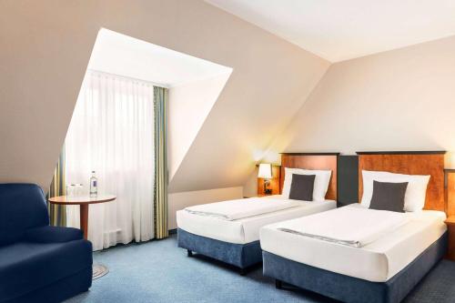 um quarto de hotel com duas camas e uma cadeira em Amedia Frankfurt Russelsheim Trademark Collection by Wyndham em Rüsselsheim