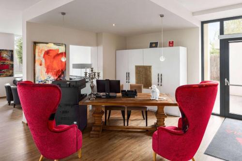 a dining room with a wooden table and red chairs at Amedia Luxury Suites Graz, Trademark Collection by Wyndham in Graz