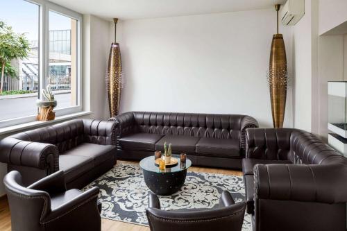 uma sala de estar com um sofá de couro e cadeiras em Amedia Luxury Suites Graz, Trademark Collection by Wyndham em Graz