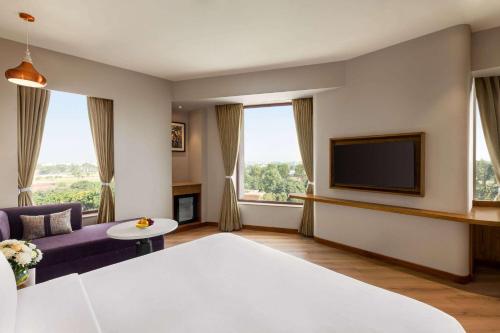 a living room with a couch and a tv at Ramada Encore by Wyndham Amritsar Airport in Amritsar